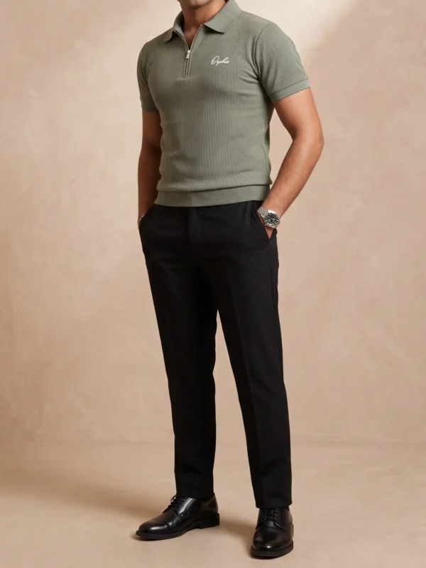 1 Model wearing Orphic men's sage green ribbed quarter-zip polo with black trousers, front view