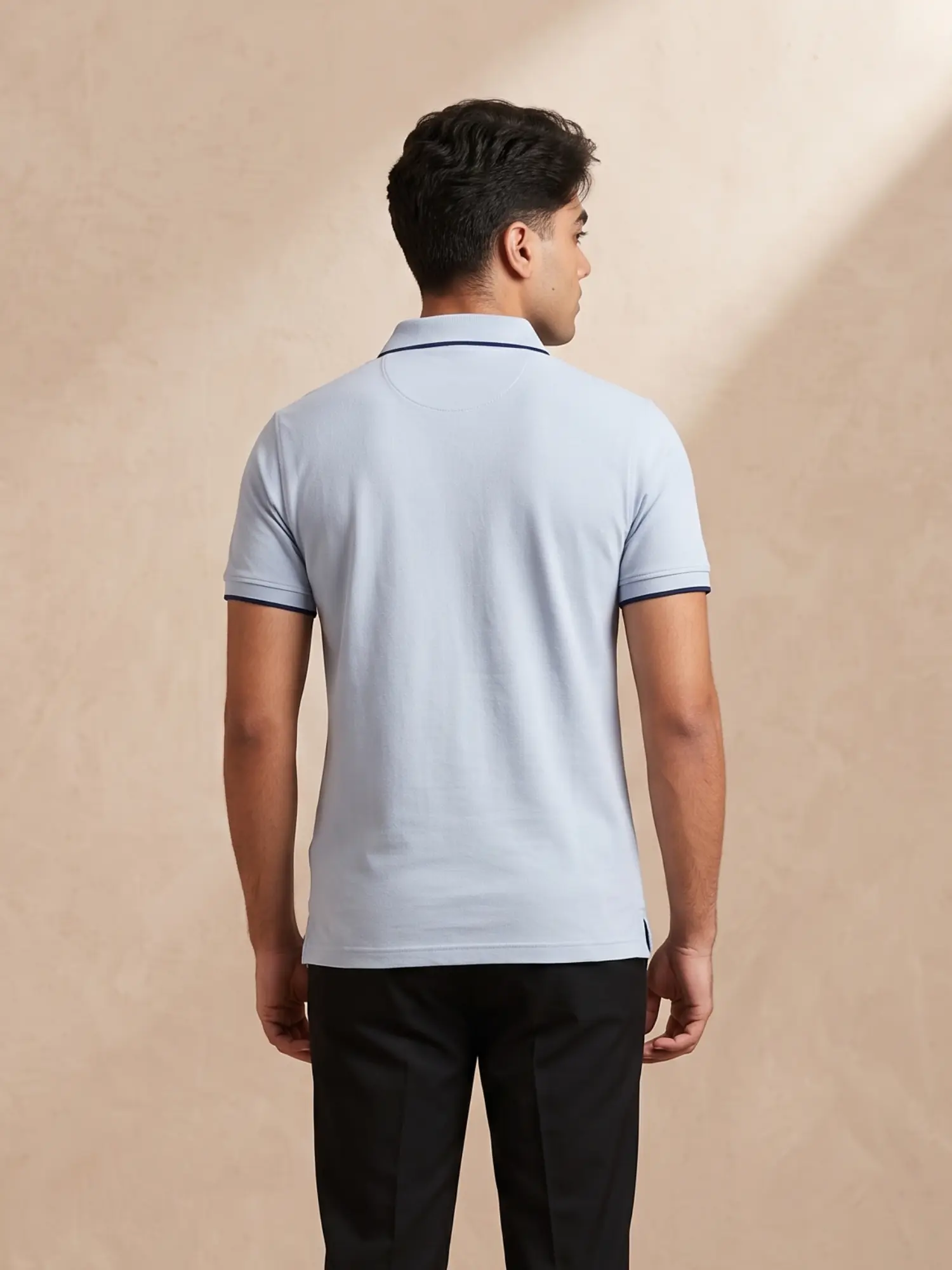 Back view of Orphic men's sky blue piqué polo with navy-tipped collar and cuffs, worn by model