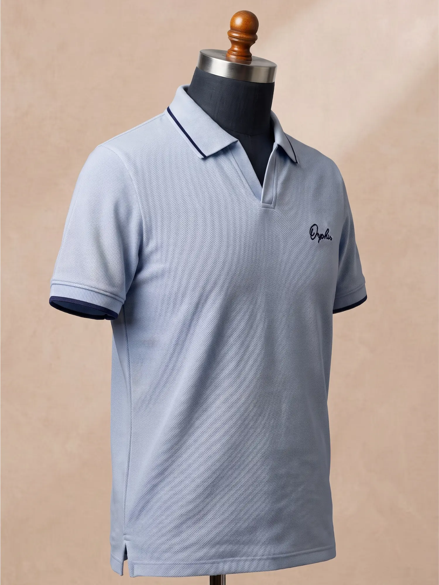 Orphic men's sky blue piqué polo with navy tipping and script embroidery, three-quarter view on display form