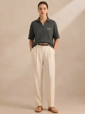 Woman wearing Orphic charcoal open-collar polo, front view with cream trousers.webp