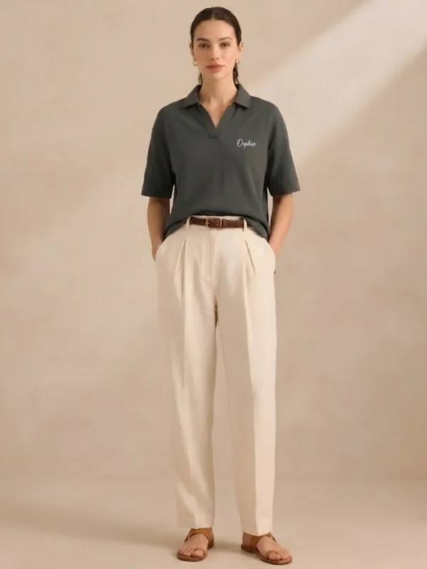 Woman wearing Orphic charcoal open-collar polo, front view with cream trousers.webp