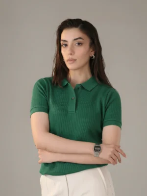 Woman wearing Orphic emerald green ribbed polo, front view.webp