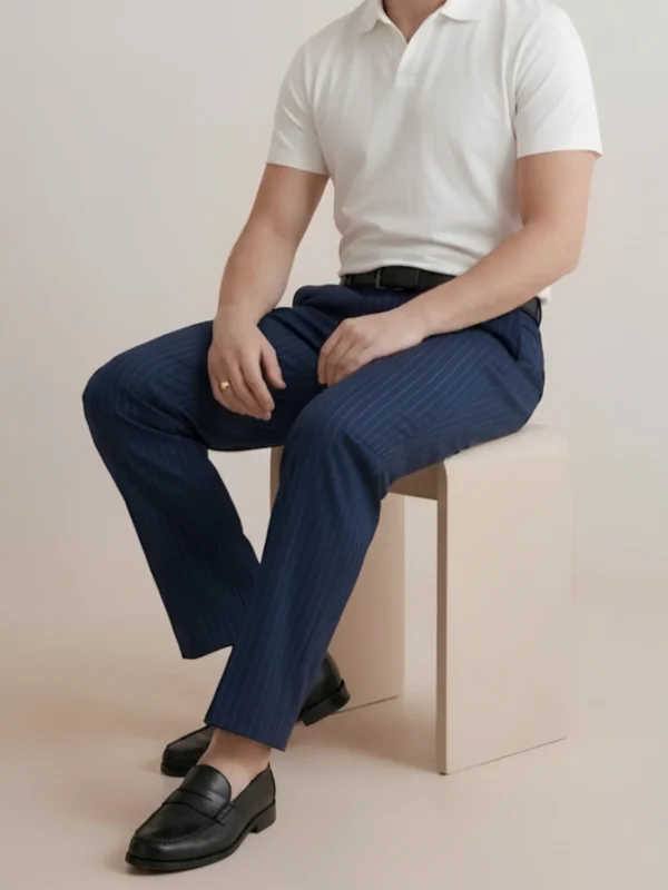 Man wearing Orphic navy pinstripe trousers seated, showing tailored drape.webp