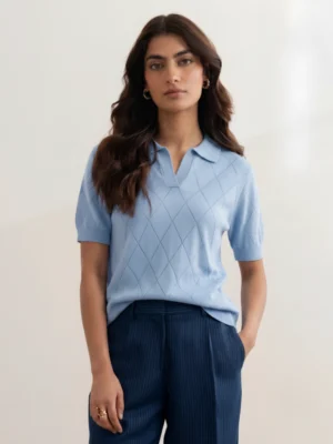 Woman wearing Orphic powder blue pointelle polo with open collar, front view.webp