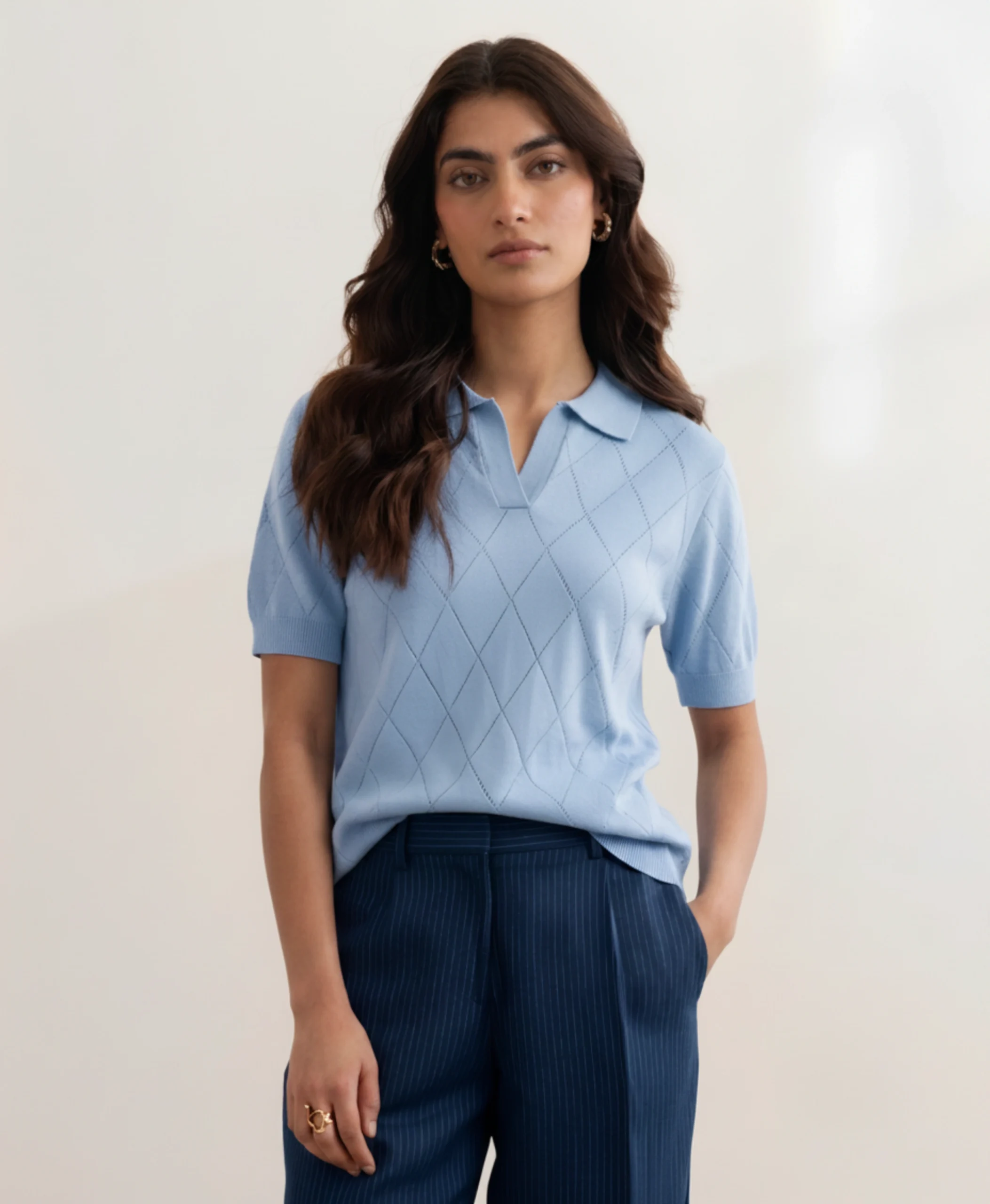 Woman wearing Orphic powder blue pointelle polo with open collar, front view.webp