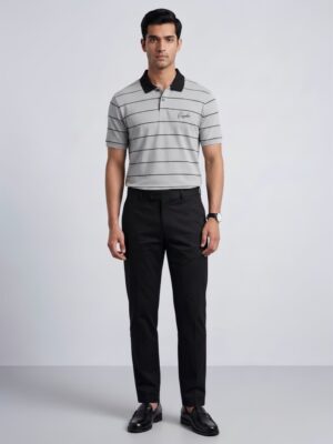 Model wearing Orphic men's grey striped polo with black collar, front view with black trousers