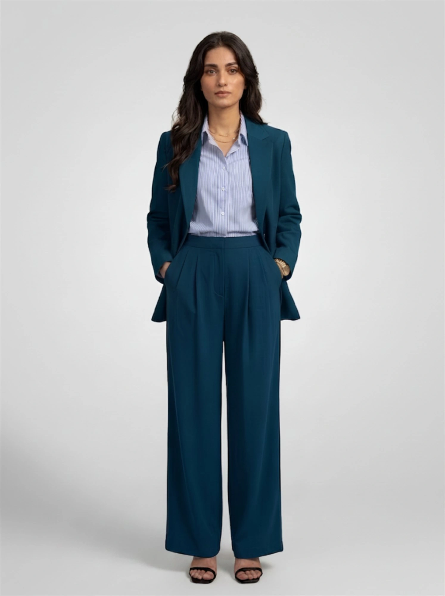 Model in Orphic women's teal trousers styled with matching blazer