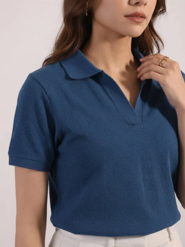 Close-up of women's denim blue polo showing open collar and textured knit