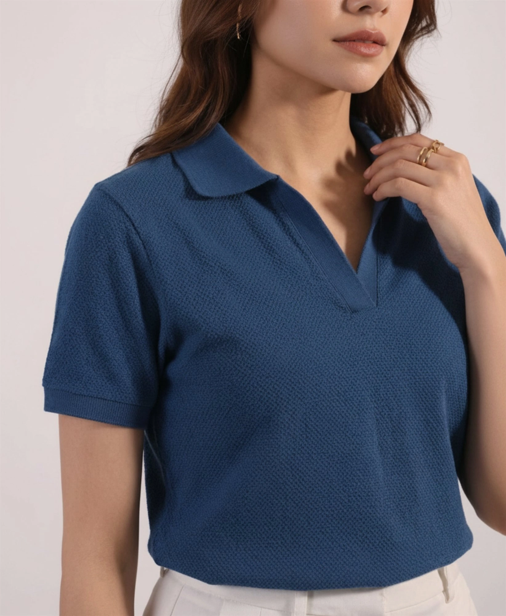 Close-up of women's denim blue polo showing open collar and textured knit