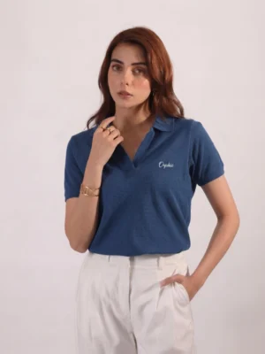 Woman wearing Orphic denim blue open-collar polo with cream embroidery, front view