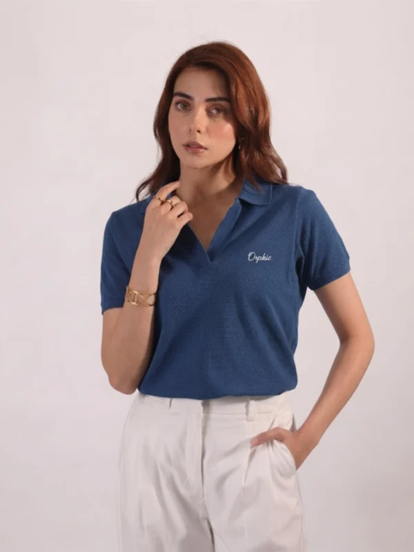 Woman wearing Orphic denim blue open-collar polo with cream embroidery, front view